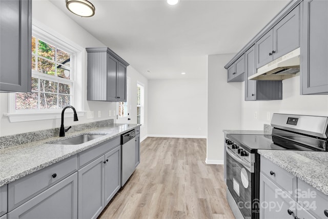 kitchen with light stone counters, sink, light hardwood / wood-style flooring, and appliances with stainless steel finishes