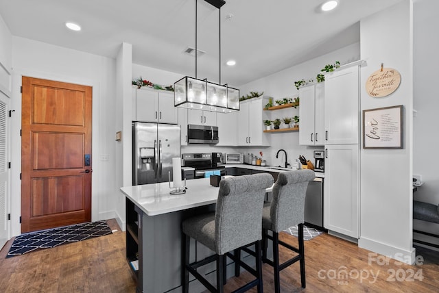 kitchen featuring pendant lighting, white cabinets, appliances with stainless steel finishes, a kitchen island, and dark hardwood / wood-style flooring