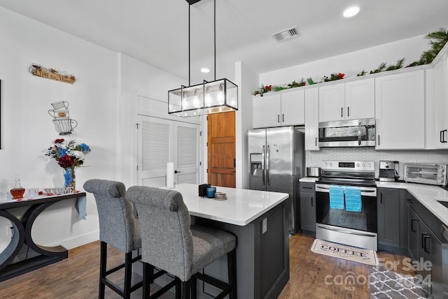 kitchen with decorative light fixtures, dark hardwood / wood-style flooring, stainless steel appliances, and white cabinetry