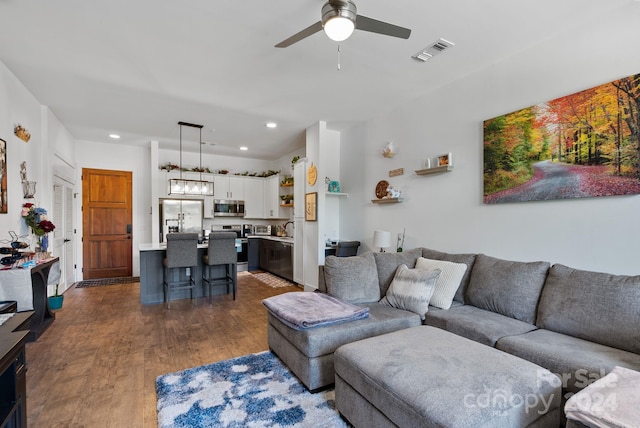 living room with ceiling fan and dark wood-type flooring