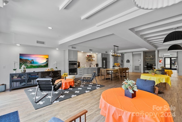 living room featuring a chandelier, sink, and light hardwood / wood-style flooring