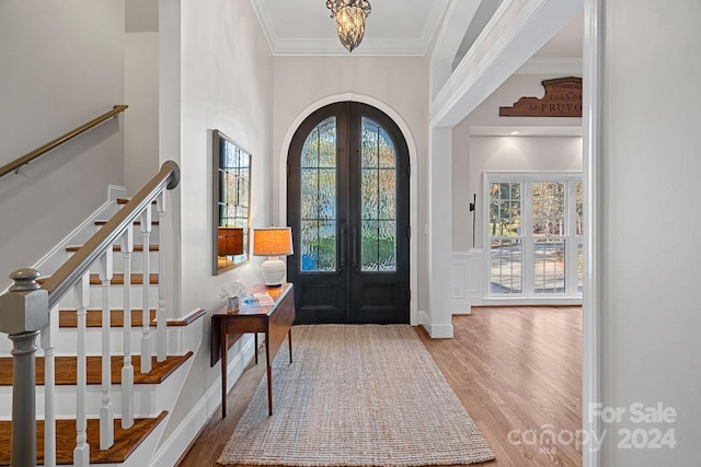 foyer featuring crown molding, french doors, a notable chandelier, and hardwood / wood-style flooring