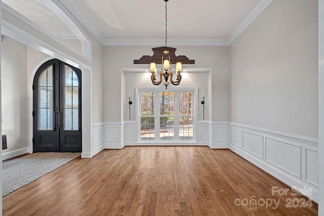 entrance foyer with a wealth of natural light, french doors, crown molding, and light wood-type flooring