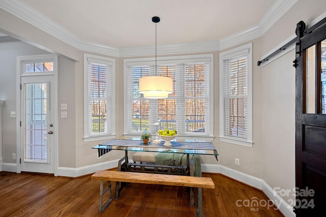 dining room with a barn door, wood-type flooring, a healthy amount of sunlight, and ornamental molding