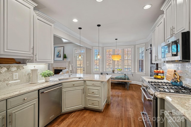 kitchen with hardwood / wood-style floors, pendant lighting, sink, decorative backsplash, and appliances with stainless steel finishes