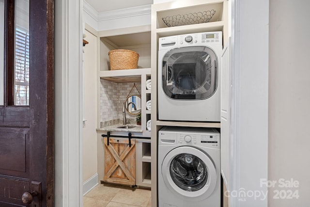 washroom featuring stacked washer / dryer, sink, light tile patterned floors, and a barn door