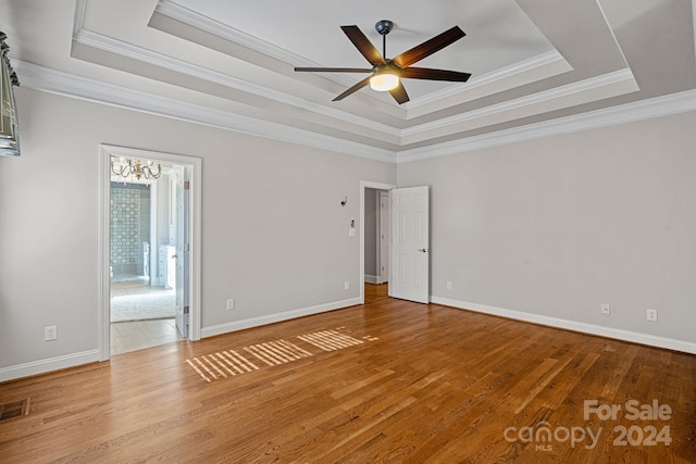 unfurnished room with a tray ceiling, crown molding, ceiling fan, and wood-type flooring