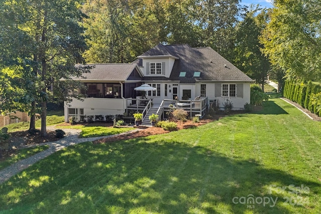 rear view of property with a lawn, a sunroom, and a deck