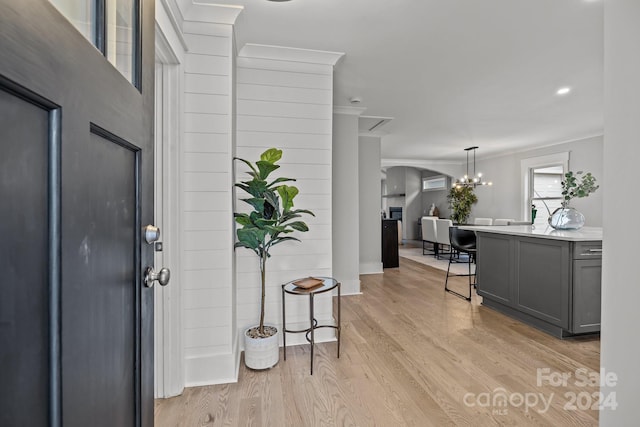 entrance foyer featuring ornamental molding, a notable chandelier, and light wood-type flooring