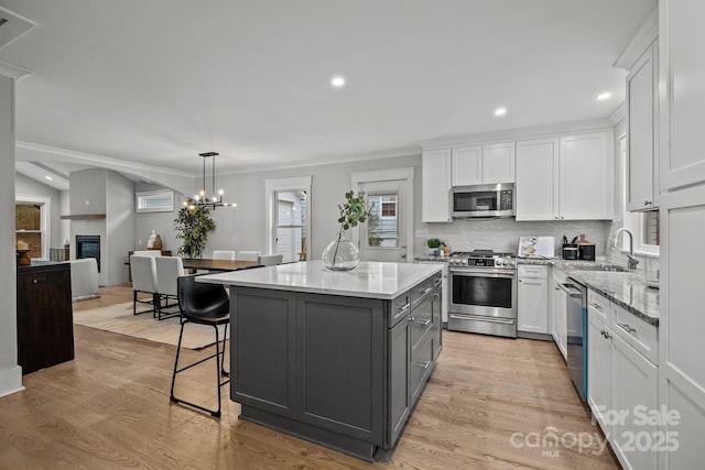 kitchen featuring a kitchen island, white cabinetry, appliances with stainless steel finishes, and decorative light fixtures