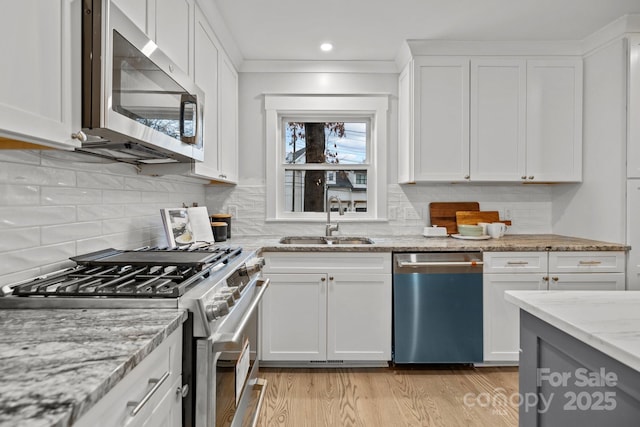 kitchen with light stone countertops, white cabinetry, appliances with stainless steel finishes, and sink