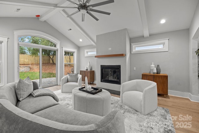 living room with vaulted ceiling with beams, a wealth of natural light, a fireplace, and wood-type flooring