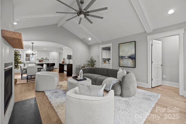 living room featuring vaulted ceiling with beams, ceiling fan, and light wood-type flooring