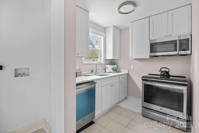 kitchen with light tile patterned floors, appliances with stainless steel finishes, sink, and white cabinets