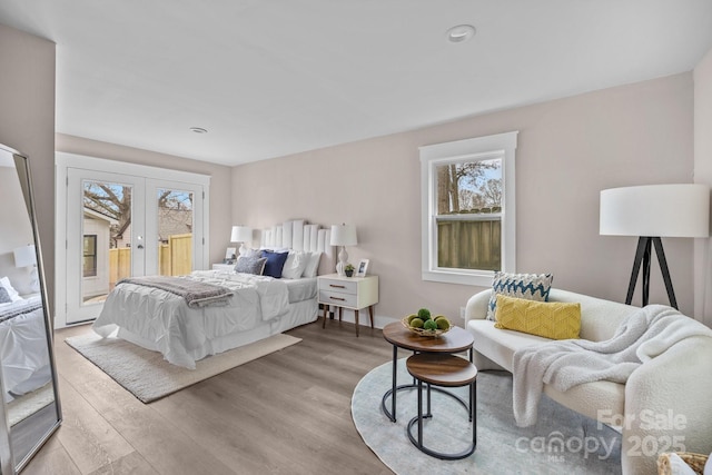 bedroom featuring access to outside, light hardwood / wood-style floors, and french doors