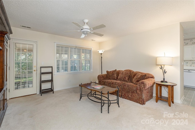 carpeted living room featuring ceiling fan and a textured ceiling