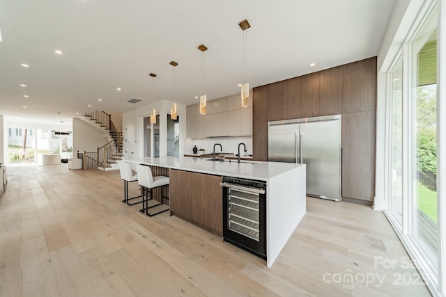 kitchen featuring a spacious island, beverage cooler, built in fridge, and pendant lighting