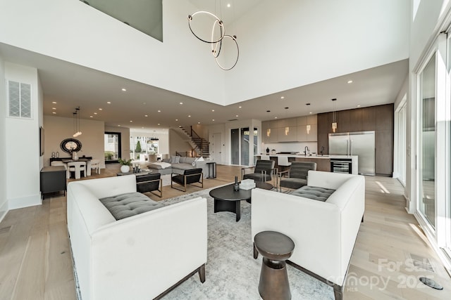 living room with a high ceiling, indoor wet bar, and light hardwood / wood-style flooring