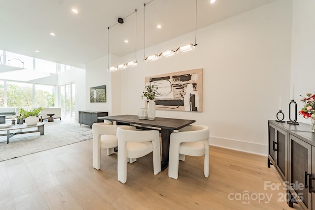 dining area with light hardwood / wood-style flooring and a high ceiling