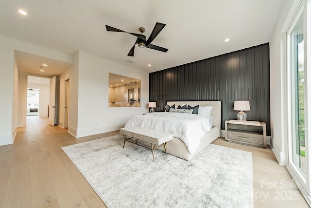 bedroom with ceiling fan, light hardwood / wood-style floors, and multiple windows