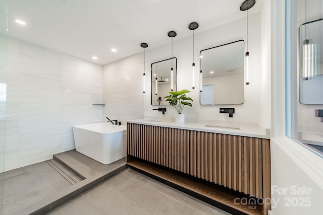 bathroom with vanity, a bathing tub, tile patterned flooring, and tile walls