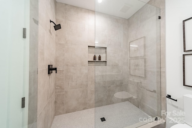 bathroom featuring toilet and a shower with shower door