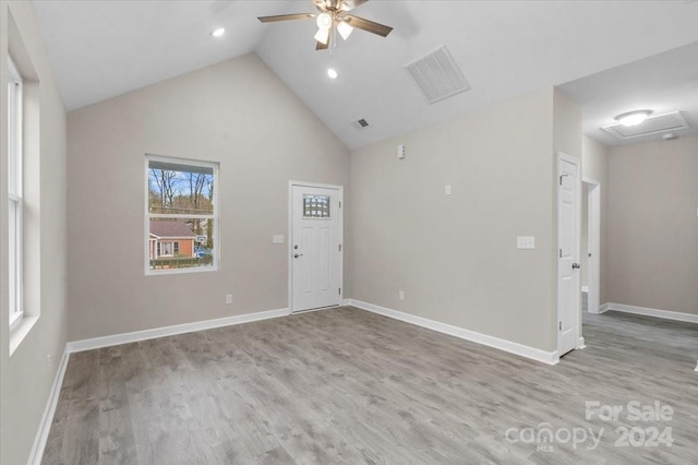 empty room featuring light wood-type flooring, high vaulted ceiling, and ceiling fan