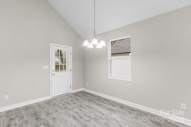 unfurnished dining area featuring a notable chandelier, high vaulted ceiling, and light hardwood / wood-style flooring