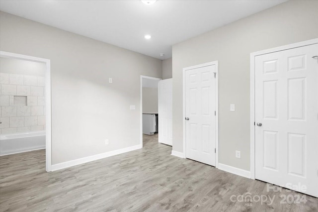 unfurnished bedroom featuring light wood-type flooring and ensuite bathroom