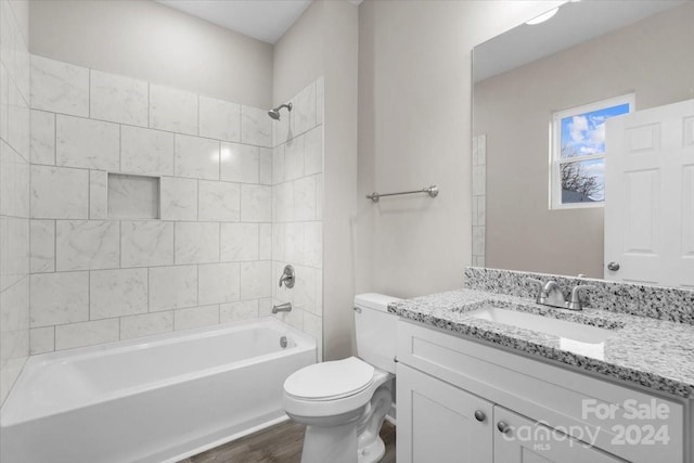 full bathroom featuring hardwood / wood-style floors, vanity, tiled shower / bath combo, and toilet