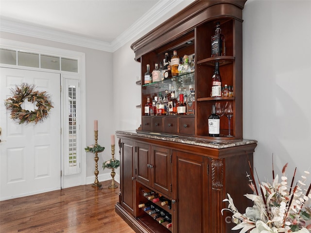 bar with dark hardwood / wood-style flooring, dark brown cabinets, and ornamental molding