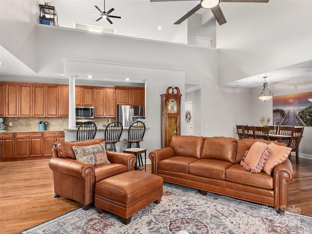 living room with high vaulted ceiling, ceiling fan, and light hardwood / wood-style floors