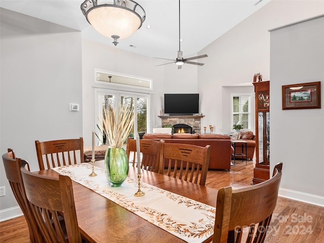 dining space featuring a stone fireplace, a healthy amount of sunlight, and wood-type flooring