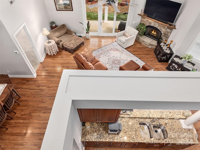 living room featuring a stone fireplace, ornate columns, and hardwood / wood-style flooring