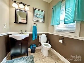 bathroom with tile patterned flooring, vanity, toilet, and a wealth of natural light