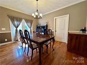 dining space featuring hardwood / wood-style floors, ornamental molding, and a notable chandelier