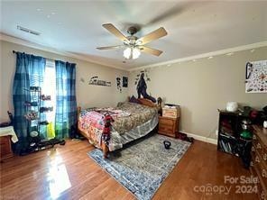 bedroom with ceiling fan, wood-type flooring, and ornamental molding