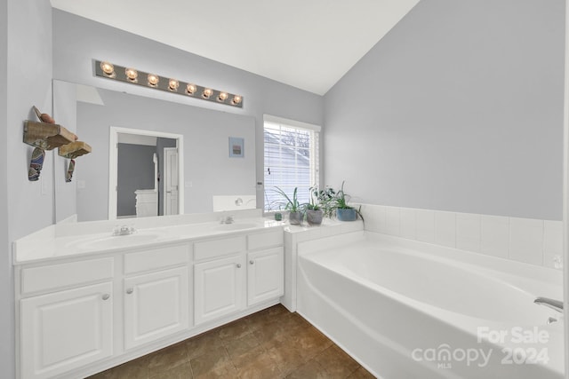 bathroom with vanity, lofted ceiling, and a washtub