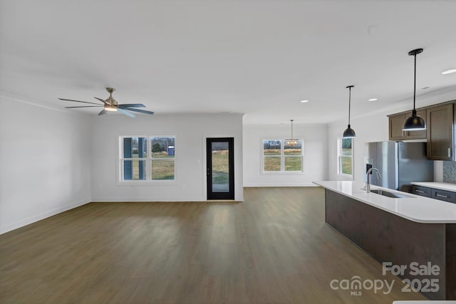 kitchen featuring decorative light fixtures, an island with sink, sink, stainless steel refrigerator with ice dispenser, and dark brown cabinets