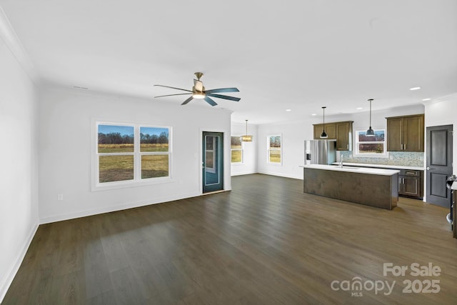 unfurnished living room with ceiling fan, sink, crown molding, and dark hardwood / wood-style floors