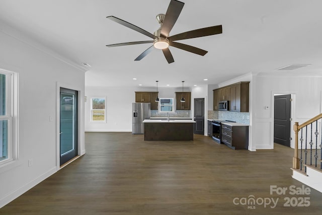 kitchen featuring a kitchen island, decorative light fixtures, backsplash, stainless steel appliances, and crown molding