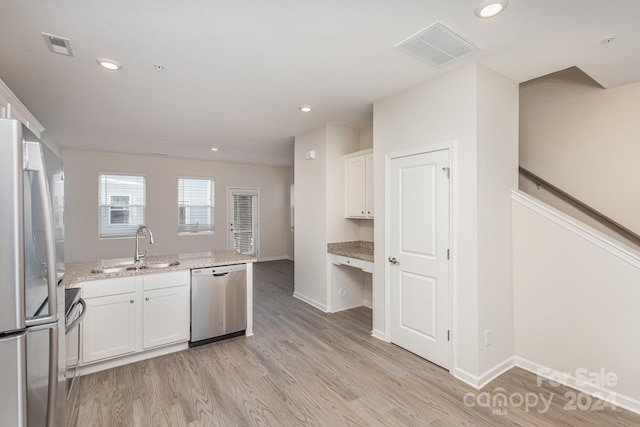 kitchen with white cabinetry, light hardwood / wood-style floors, appliances with stainless steel finishes, and light stone counters