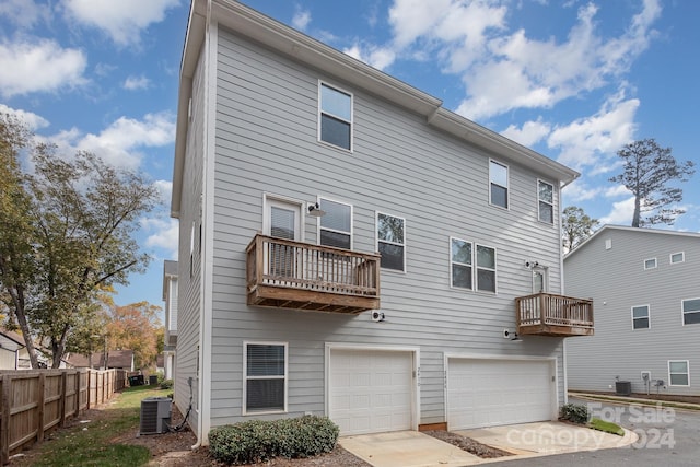 back of property featuring a balcony, central AC, and a garage