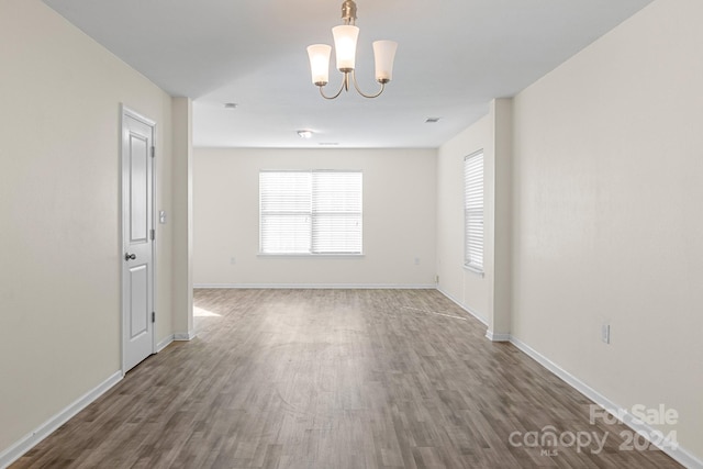 empty room featuring a notable chandelier and hardwood / wood-style flooring