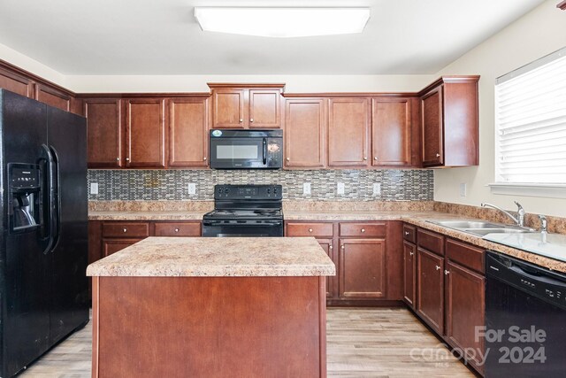 kitchen with black appliances, light hardwood / wood-style floors, a kitchen island, and sink