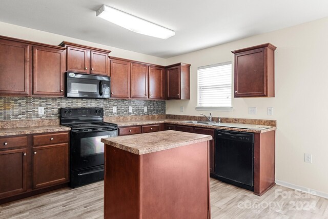 kitchen featuring sink, backsplash, a kitchen island, black appliances, and light wood-type flooring