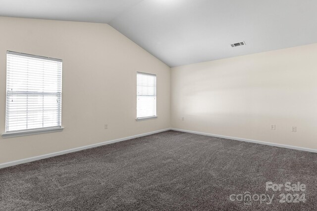 carpeted spare room featuring vaulted ceiling