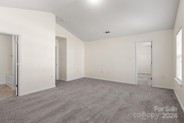 carpeted spare room featuring lofted ceiling