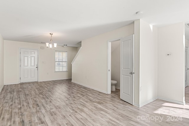 spare room with a notable chandelier and light hardwood / wood-style flooring