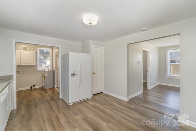 kitchen with light hardwood / wood-style floors, white fridge with ice dispenser, white cabinetry, and a wealth of natural light